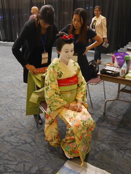 Masayo applying makeup to geisha model at Expo